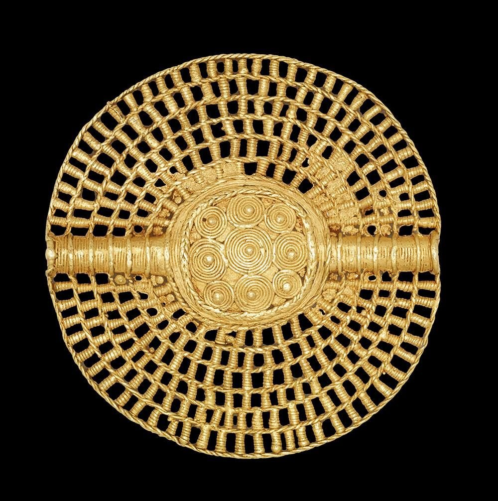 A circular gold pendant with intricate woven rings and a central sphere adorned with golden spirals.