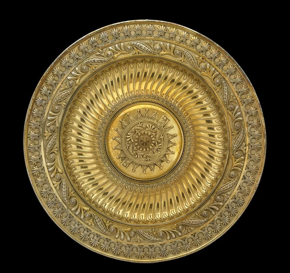 An golden circular dish with intricate detailing and an ornate many-sided star at its centre.