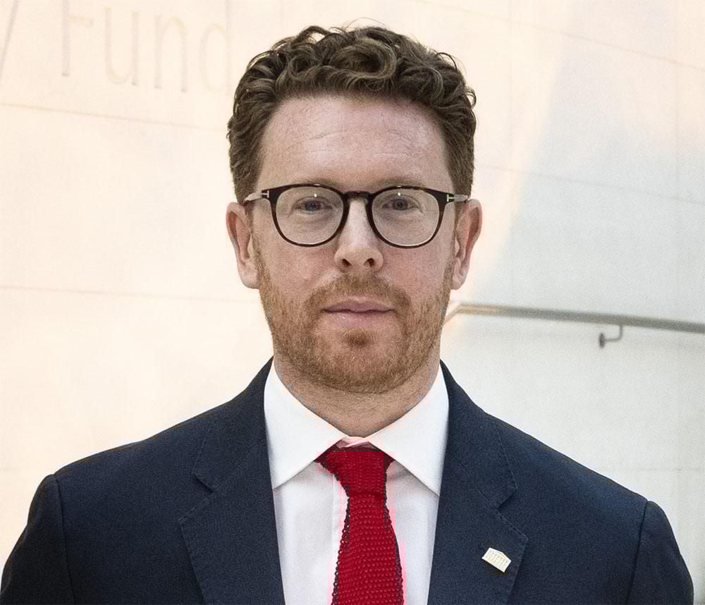Headshot of Dr Nicholas Cullinan OBE wearing a suit and tie.