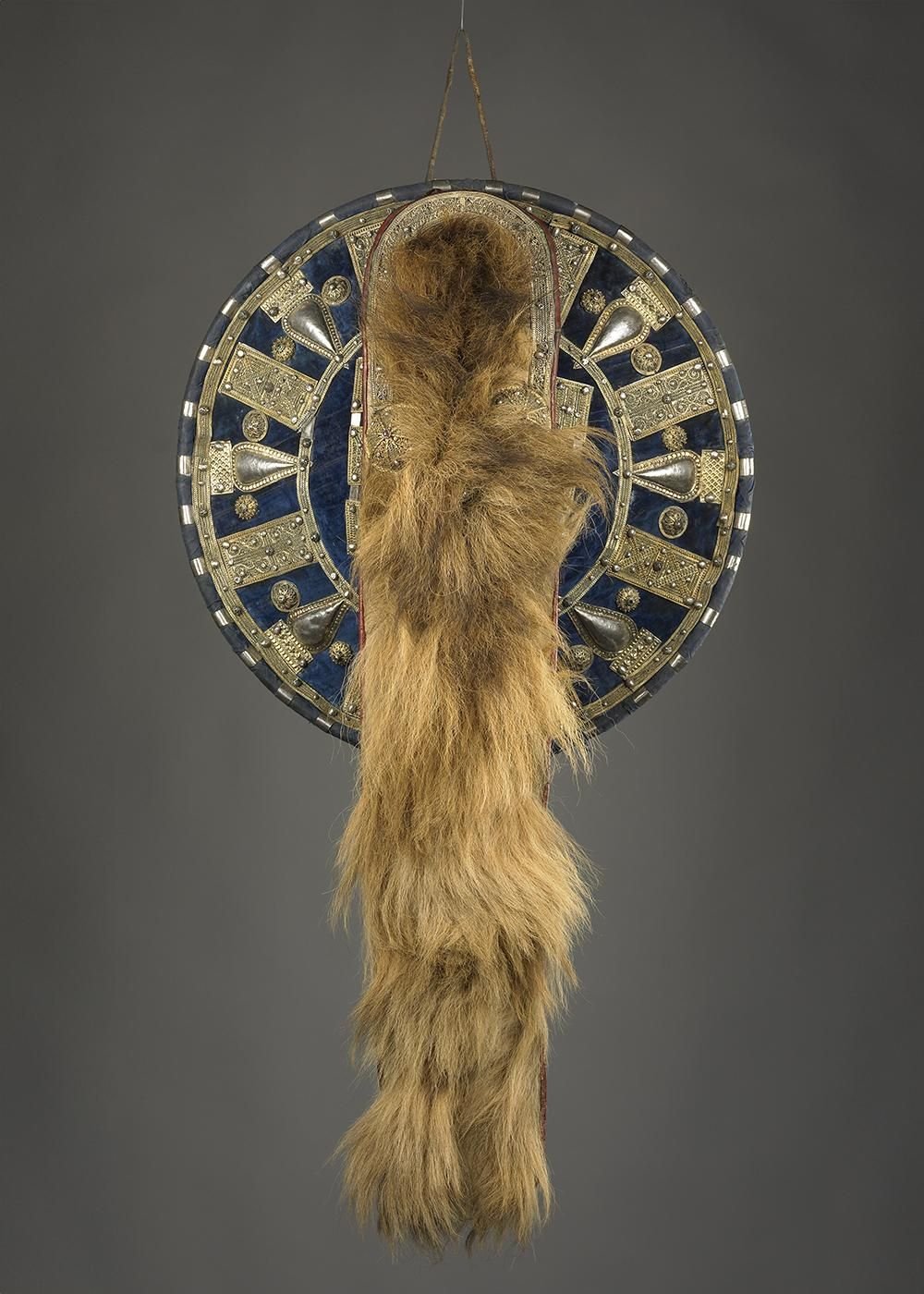 Ornate circular shield with a long strand of fur hanging from the middle.