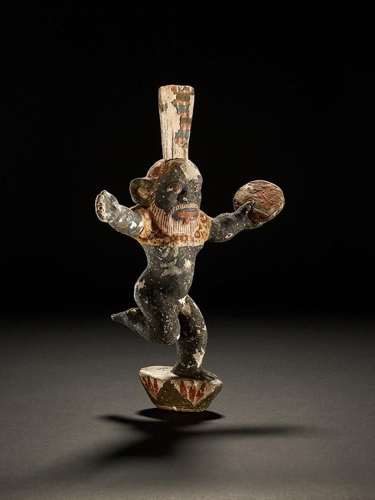 Wooden figure of Bes dancing with a tambourine in one hand and standing on a lotus flower
