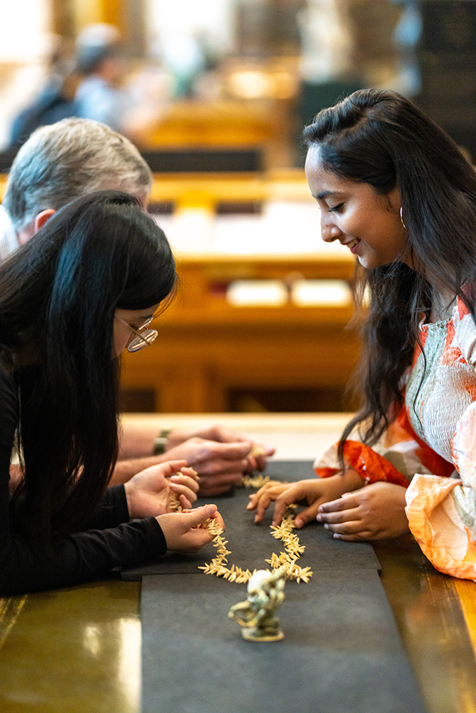 Ishani helps visitors handle a necklace resting on a black board