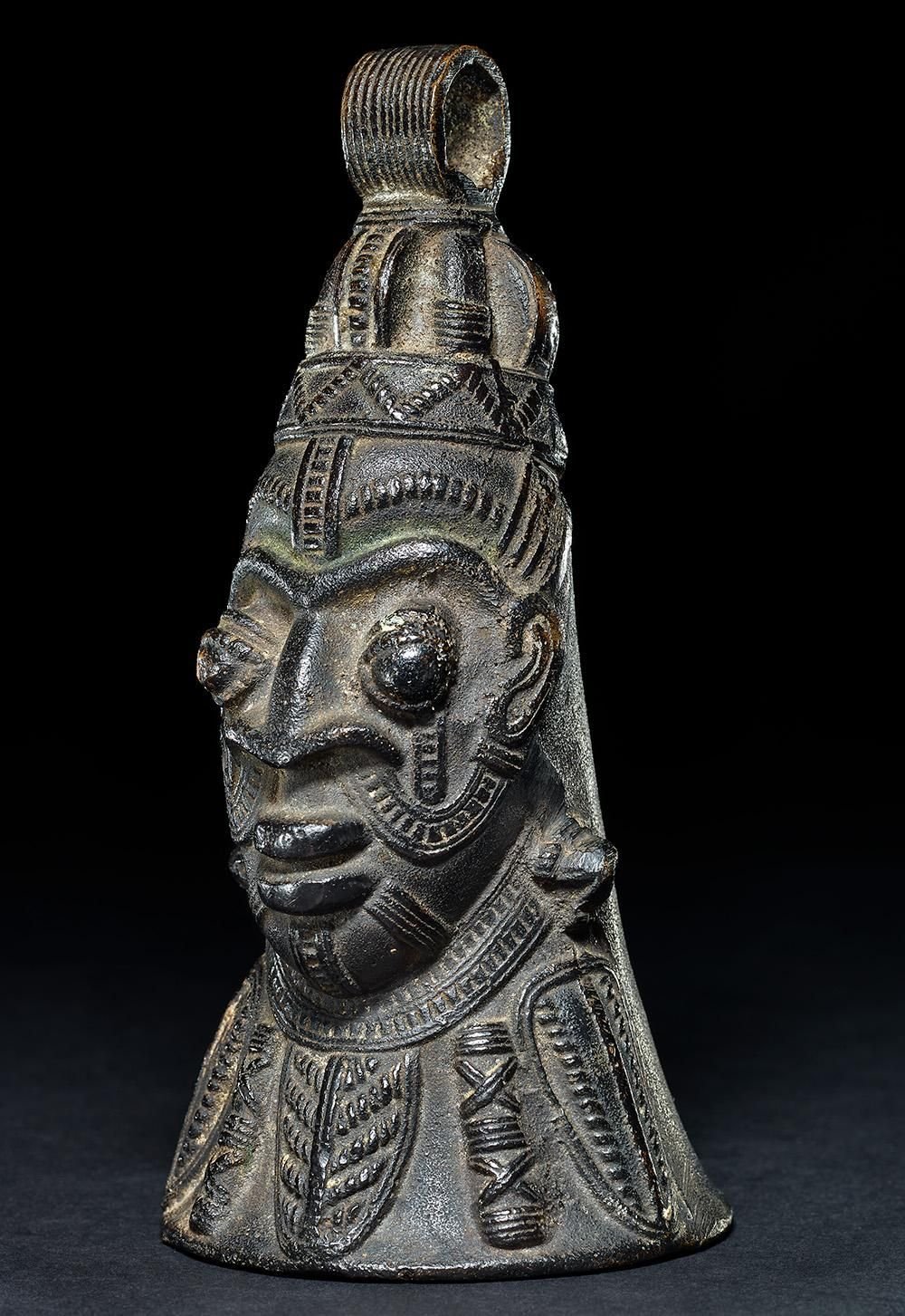 A bronze bell in the shape of a man's head with intricate decoration