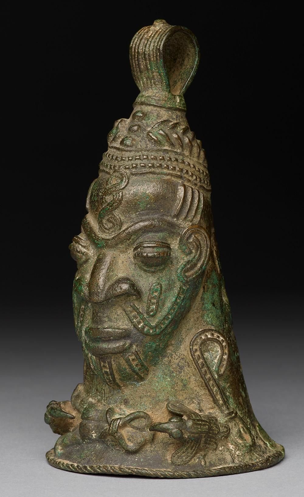 A copper alloy bell in the shape of a man's head with intricate decoration