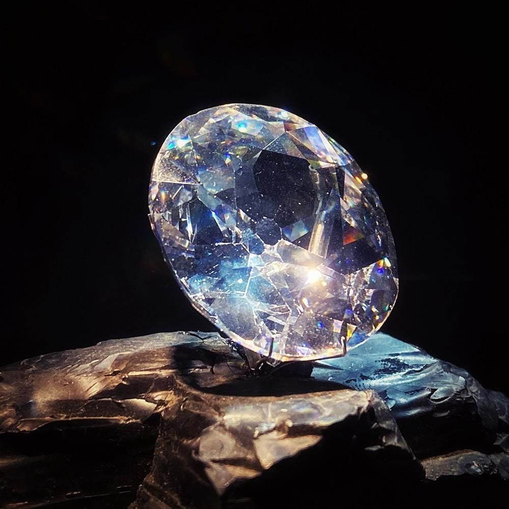 A replica of an oval, many faceted cut diamond, sitting on a rock