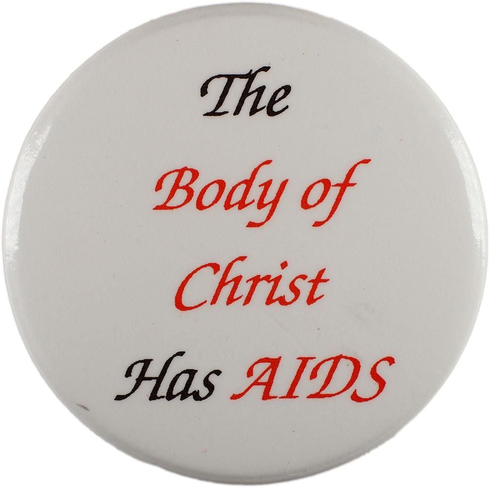 A white badge which bears the words in cursive script: The Body of Christ Has AIDS. The words 'body of Christ' and 'AIDS' are in red, while the rest of the text is black.