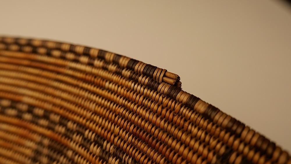 Detail of the rim of woven basketry showing alternating colours and incredible artistry