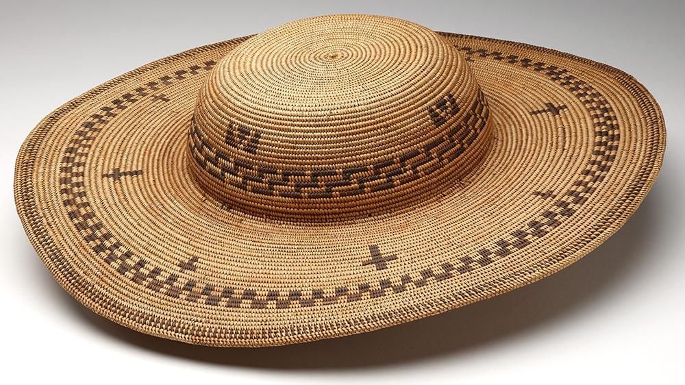 Handwoven basketry hat in a straw colour with a darker graphic pattern and crosses