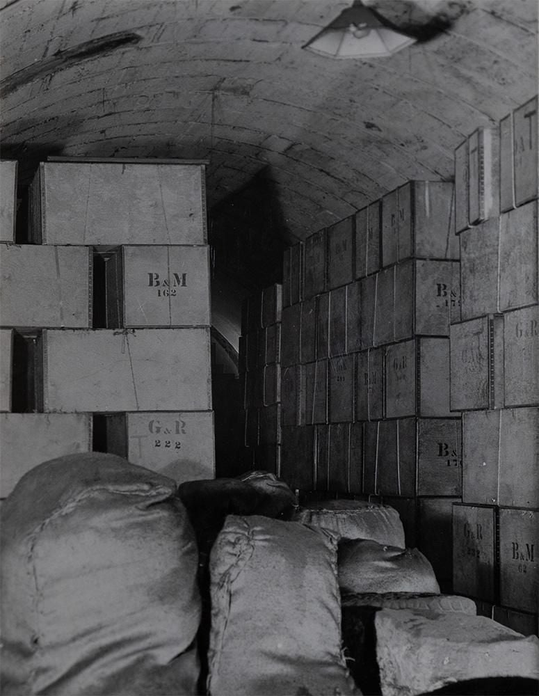 Beneath the curved roof of a tube station there are boxes piled to the ceiling with the letters 'BM' and 'GR' on them
