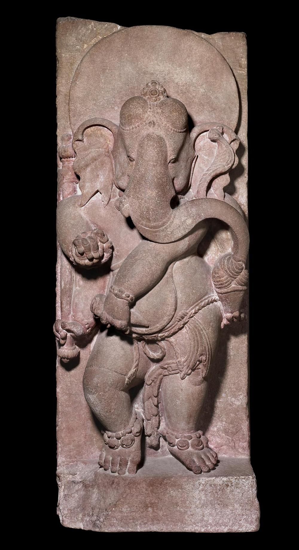Sandstone carving of the god Ganesha, with the body of a human, the head of an elephant and four arms, dancing while holding a bowl of sweets