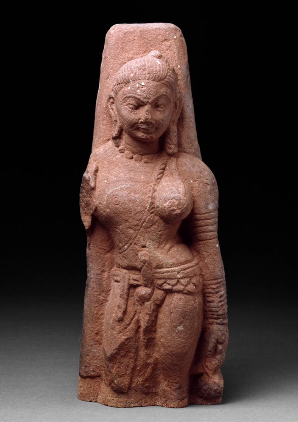 A red sandstone carving of a figure, male on one side, female on the other, representing the god and goddess Shiva and Parvati.