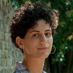 Head and shoulders photo of Hasti, who has short dark curly hair and wears hoop earrings and a striped shirt.